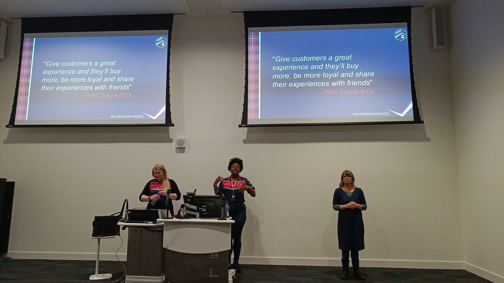 Guro Faller and Tricia Sinclair presenting at Scottish Summit with an interpreter. " large screens with their presentation on the background